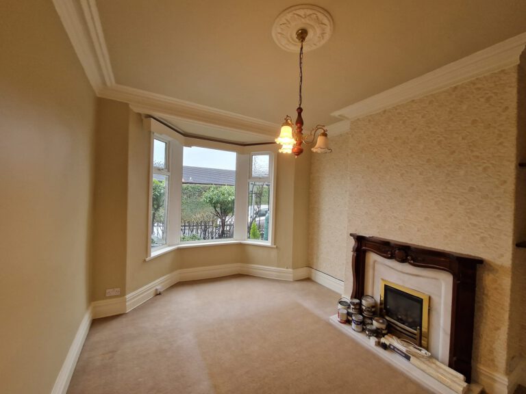 After: the same front room repainted in cream, with bay window and fireplace