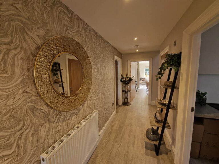 Hallway with gold swirl wallpaper and a round mirror